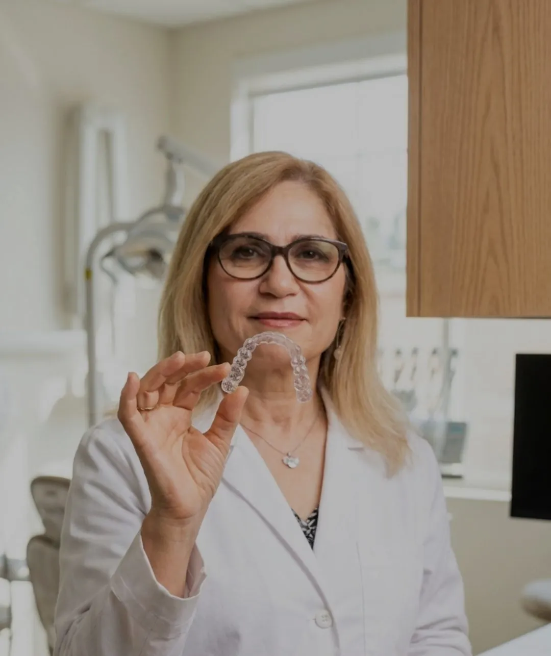Dr. Mahvash Emami holding a clear aligner in her Sunland office